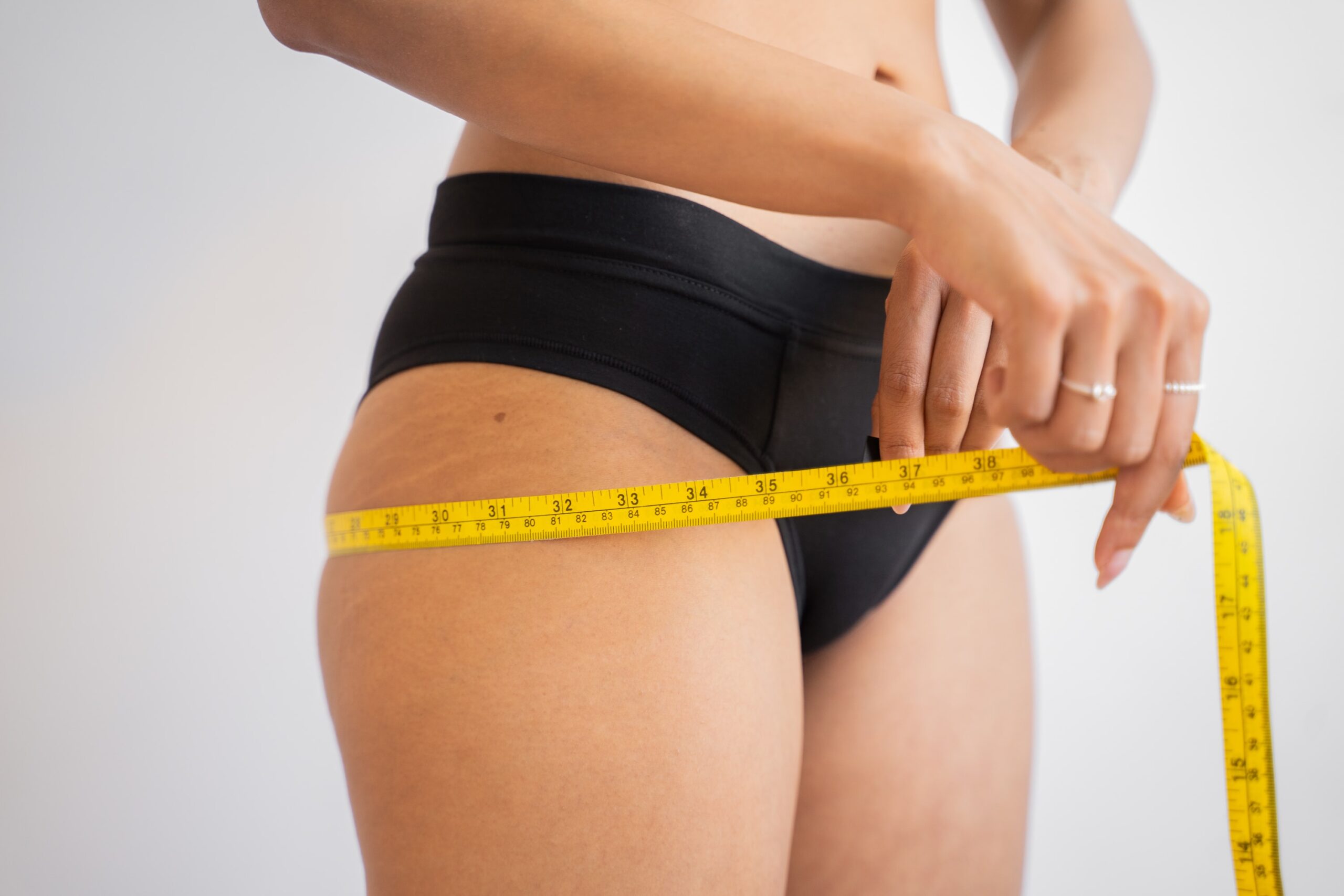 Kobieta mierzy sobie biodra po korzystaniu ze spalacza tłuszczu